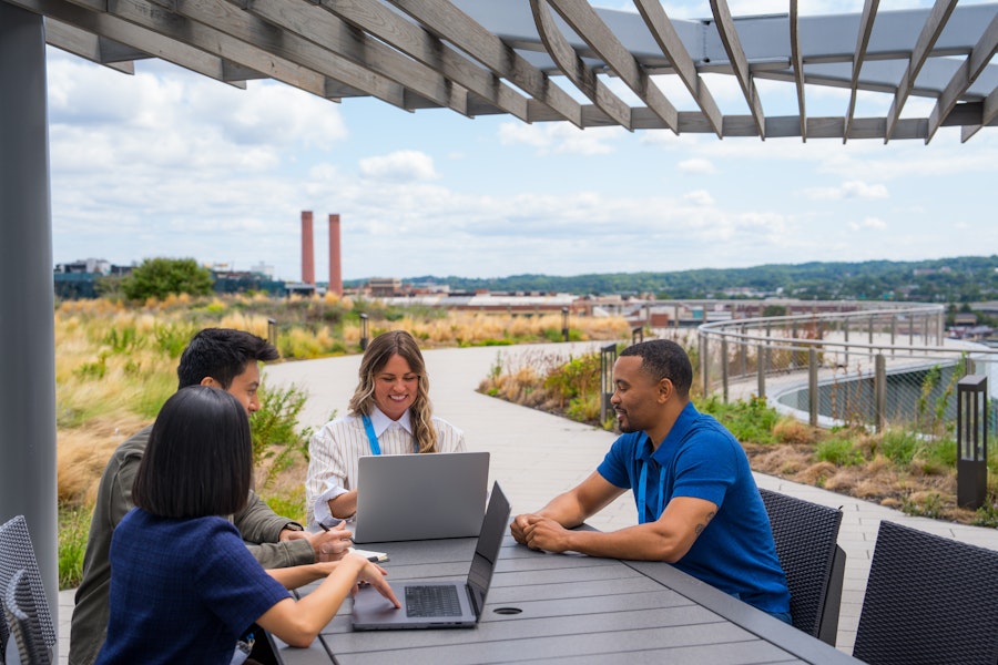 Small meeting taking place on the rooftop with grass and a bridge in the back