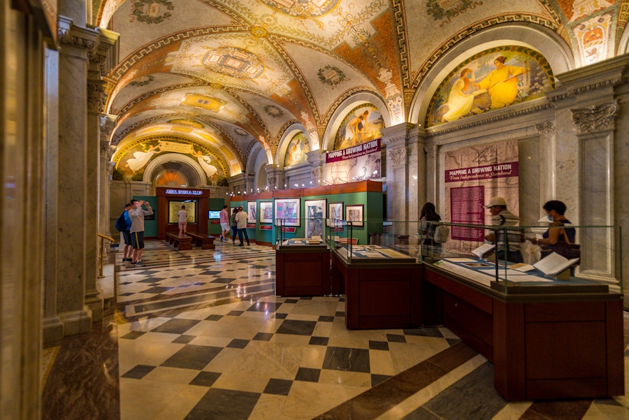 Visitors view cultural exhibits beneath a highly ornamented vaulted ceiling in the Library of Congress.