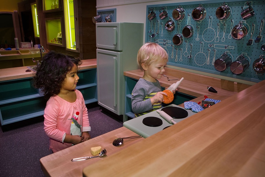 Two young children playing in a pretend kitchen at Wegmans Wonderplace in the National Museum of American History.