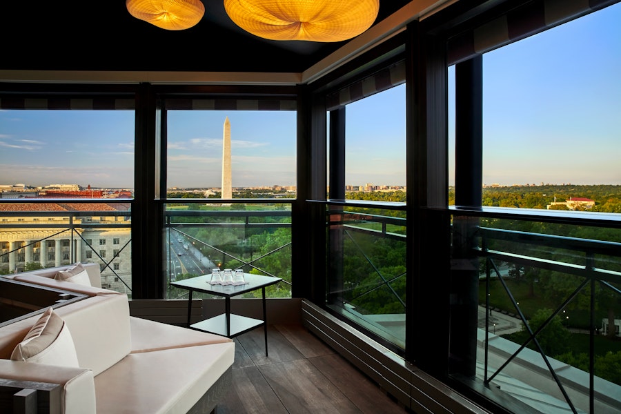 A luxurious rooftop lounge with floor-to-ceiling windows offers stunning views of the Washington Monument and the National Mall.