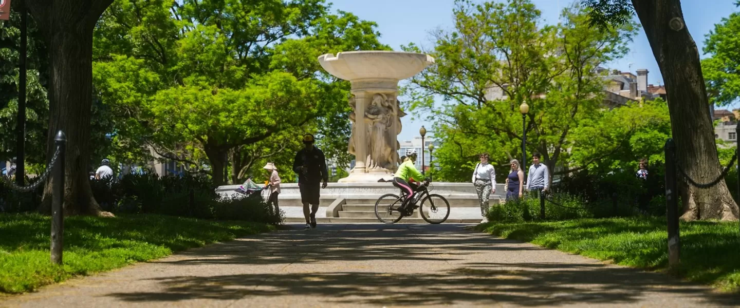 Fountain surrounded by people walking and biking