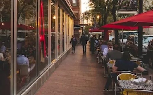 The exterior of Jaleo by José Andrés in Washington, DC, with large red neon lettering and outdoor seating under red umbrellas.
