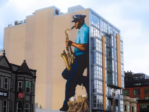 A mural on a building in Washington, DC, depicts a mailman playing the saxophone, honoring jazz musician Buck Hill.