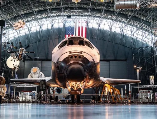The Space Shuttle Discovery displayed inside the Smithsonian’s Steven F. Udvar-Hazy Center with spacecraft exhibits surrounding it.