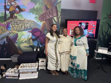 Three women in traditional Ethiopian attire stand together during an Ethiopian New Year lunch and learn presentation.