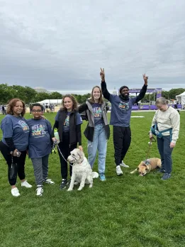 A group of coworkers and two dogs pose on the National Mall during a Best Buddies walk in Washington, DC.